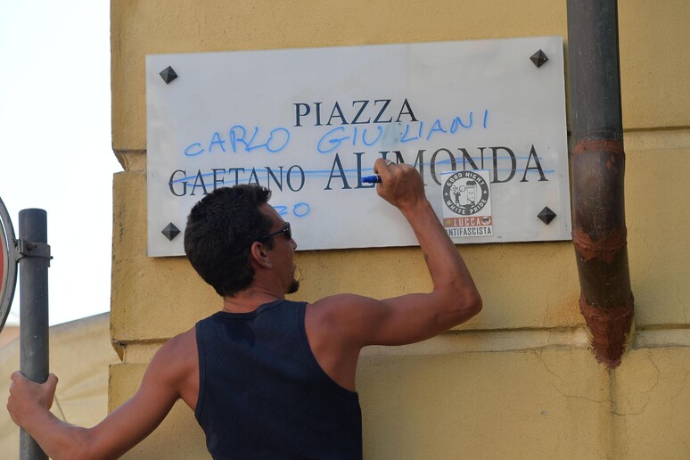 G8: un giovane scrive Carlo Giuliani sulla targa in piazza Alimonda - RIPRODUZIONE RISERVATA