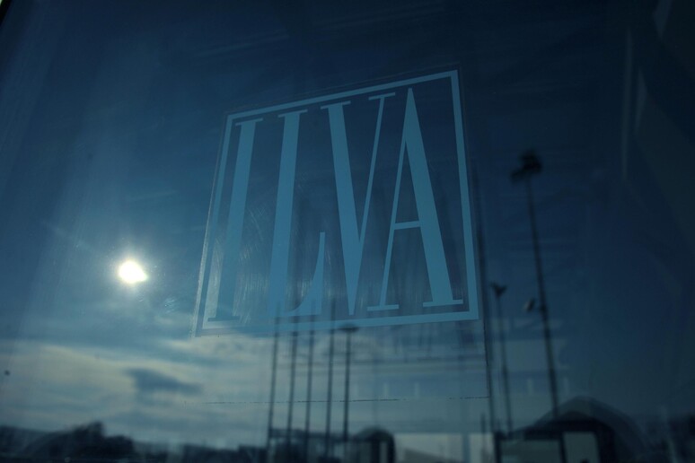 Il marchio ILVA si riflette su un vetro delle portineria dello stabilimento di Genova - RIPRODUZIONE RISERVATA