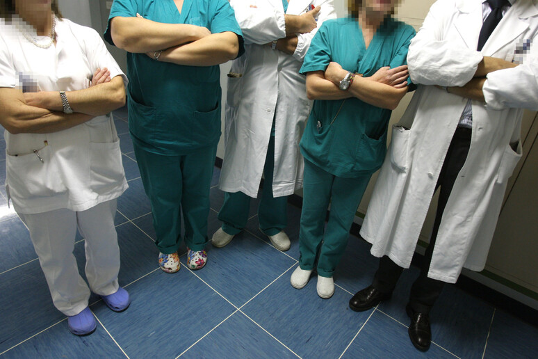 Un gruppo tra medici e paramedici incrocia le braccia in una foto d 'archivio - RIPRODUZIONE RISERVATA