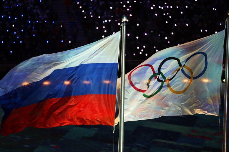 La bandiera olimpica e la bandiera russa durante la cerimonia di chiusura dei Giochi a Sochi nel 2014 © ANSA/EPA