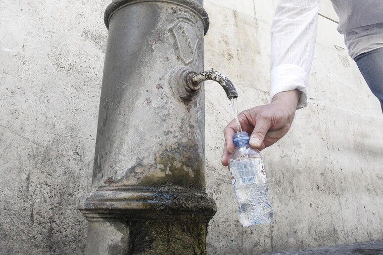 Un turista riempie d 'acqua le sua bottiglietta da una fontanella pubblica in piazza del Pantheon - RIPRODUZIONE RISERVATA
