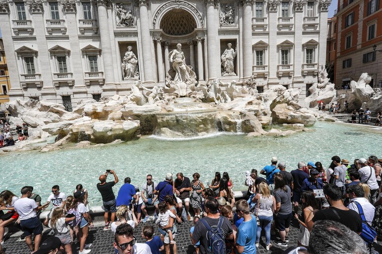 Turisti in piazza della Fontana di Trevi in una foto di archivio - RIPRODUZIONE RISERVATA