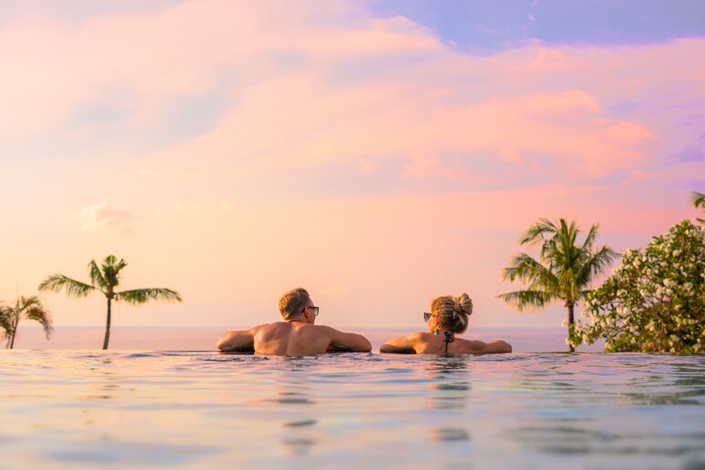 Una coppia si rilassa nell 'acqua di una infinity pool. foto iStock. - RIPRODUZIONE RISERVATA
