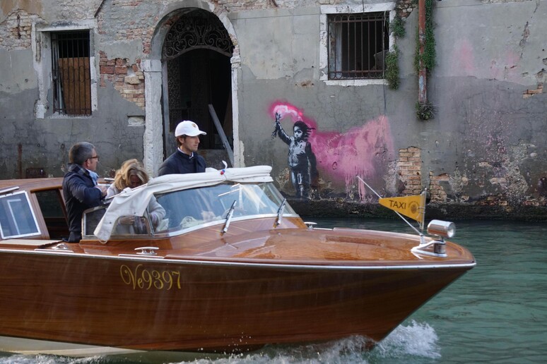 A motorboat passes in front of the alleged work of the American street artist Bansky, just called  "The shipwrecked child", who appeared this morning on the outer wall of a house overlooking the Rio  C Foscari in Venice, Italy, May 14, 2019. - RIPRODUZIONE RISERVATA