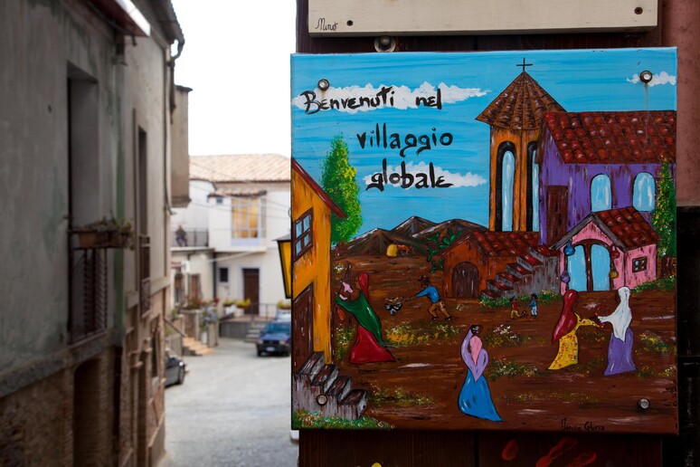 Uno dei murales del villaggio globale che raccoglie migranti provenienti da diverse parti del mondo, Riace (Reggio Calabria), archivio - RIPRODUZIONE RISERVATA