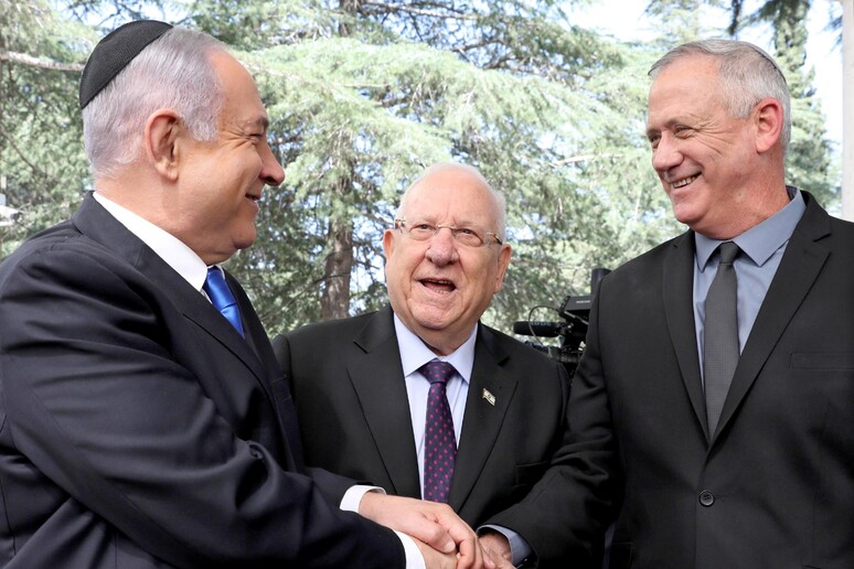 Banyamin Netanyahu (s) e benny Gantz (d) si stringono la mano davanti al presidente d 'Israele, Reuven Rivlin (c) © ANSA/EPA