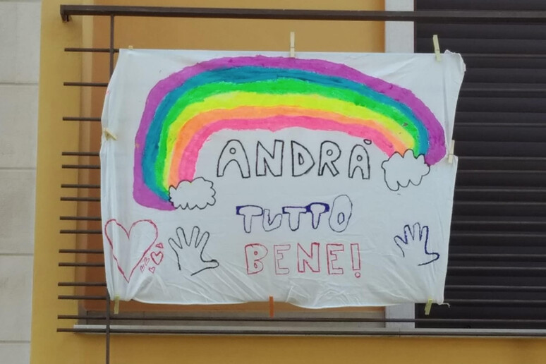 Un arcobaleno e la scritta "andrà tutto bene" dipinti dai bambini - RIPRODUZIONE RISERVATA