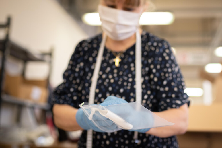 Una donna al lavoro con guanti e mascherine - RIPRODUZIONE RISERVATA