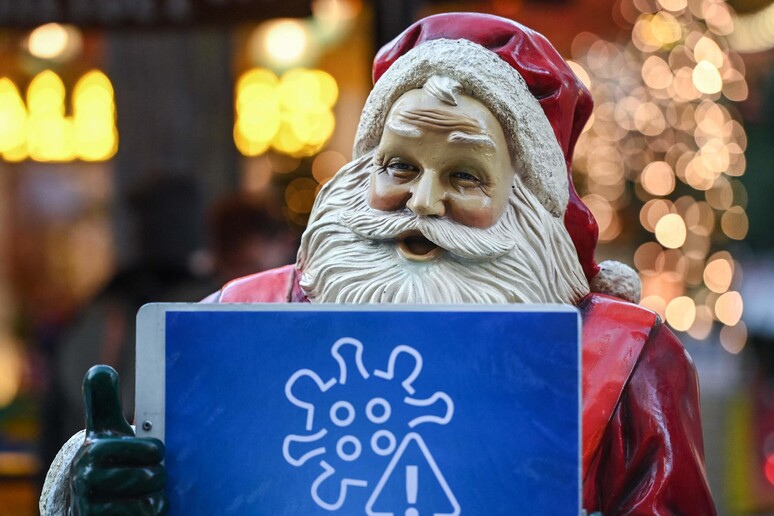 Una statua di Babbo Natale all 'ingresso di un mercatino natalizio mostra le avvertenze per evitare la diffusione del Covid © ANSA/AFP