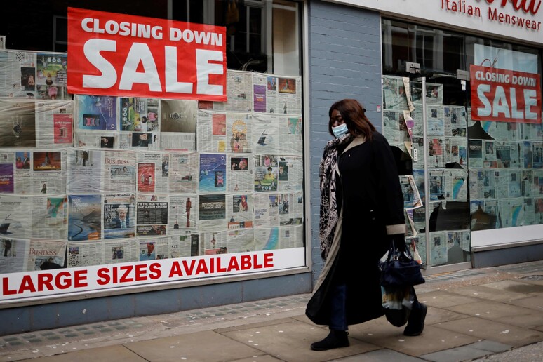 Un passante cammina davanti a una vetrina a Londra © ANSA/AFP