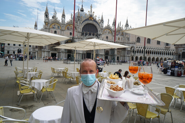 Un cameriere dello storico Caffè Lavena al lavoro, in piazza San Marco - RIPRODUZIONE RISERVATA