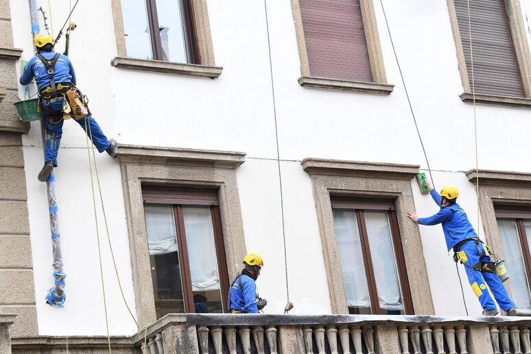 Operai acrobati al lavoro su un facciata di un palazzo a Milano - RIPRODUZIONE RISERVATA