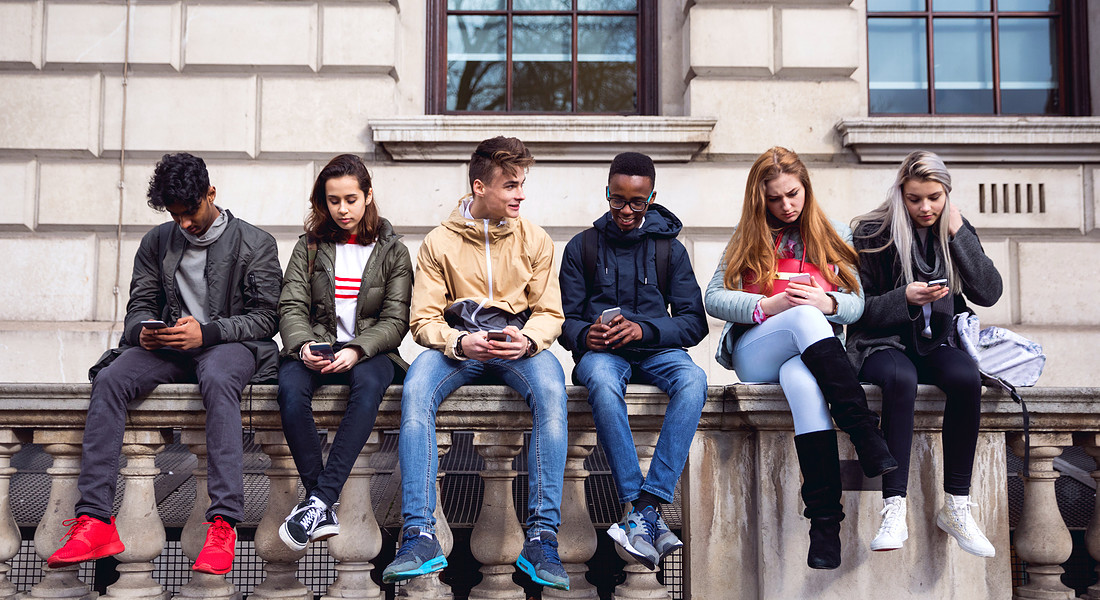 Un gruppo di adolescenti, tutti rigorosamente con lo smartphone in mano foto iStock © Ansa