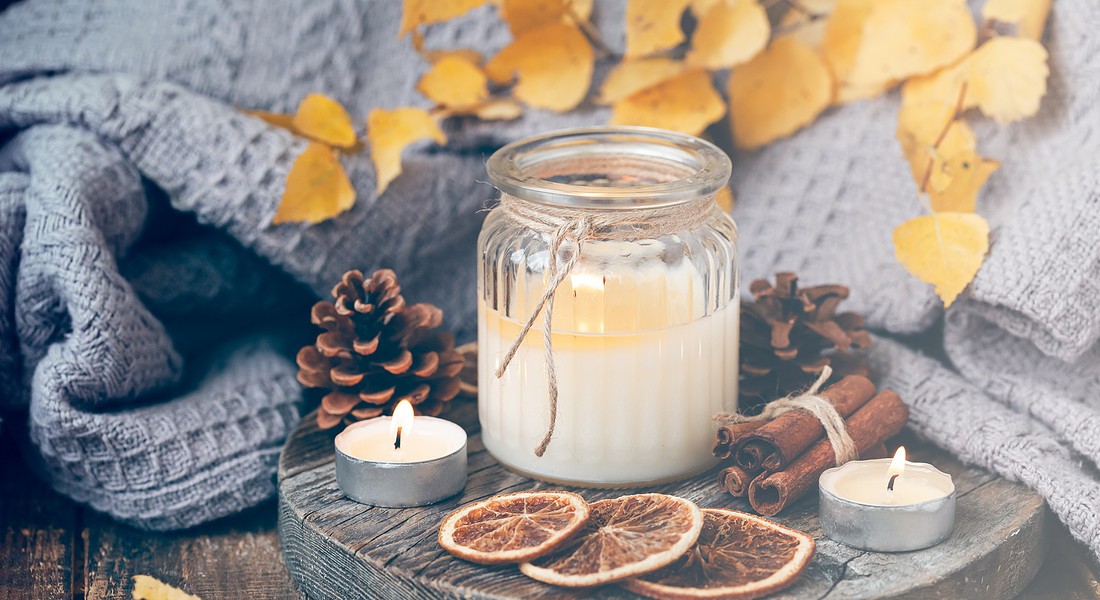 Autumn composition with aromatic candle, dry citrus, cinnamon. Aromatherapy on a grey fall morning, atmosphere of cosiness and relax. Wooden background close up © Ansa