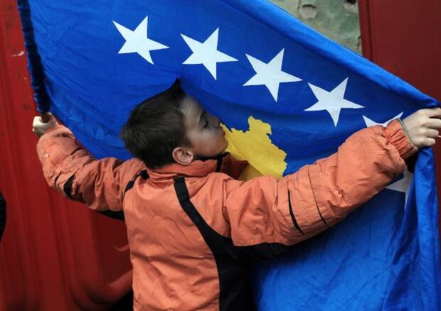 Un bambino bacia la bandiera kosovara. © ANSA 
