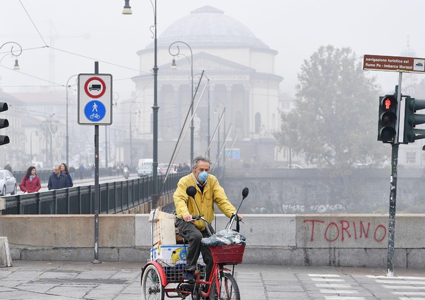 Un uomo in bici indossa la mascherina a causa dell'alto livello di smog a Torino © ANSA