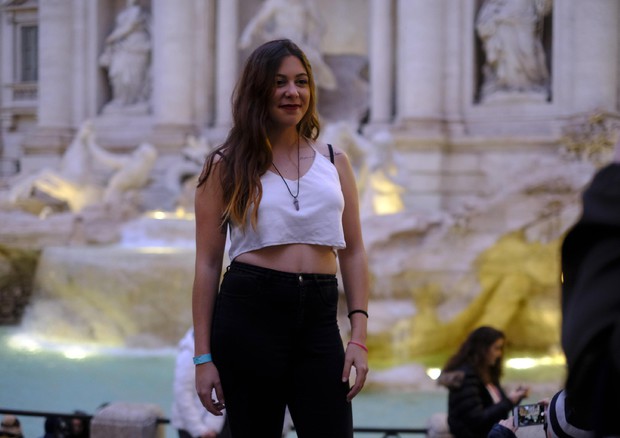 Una giovane turista in abbigliamento estivo a Fontana di Trevi © ANSA