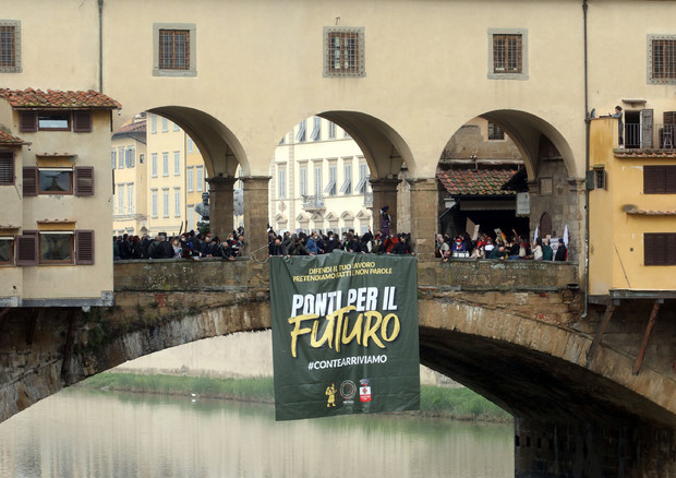 Quasi 200 persone su Ponte Vecchio a Firenze, con cartelli e striscioni, durante la manifestazione 'Marcia dei Ristoratori' che, a piedi, dal capoluogo toscano raggiungerà Roma il 13 novembre © ANSA
