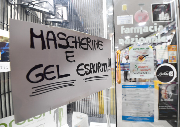 Un cartello esposto sulla vetrina esterna di una Farmacia genovese, che segnala l'esaurimento di gel  disifettanti e mascherine di protezione per il viso (archivio) © 