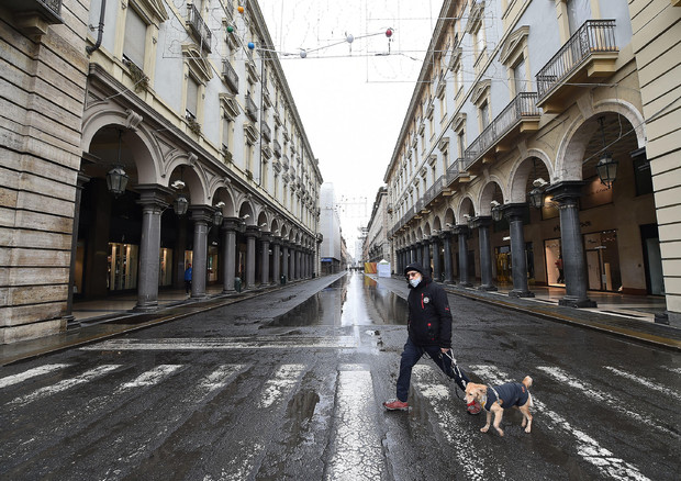 Un uomo attraversa una strada a Torino © ANSA
