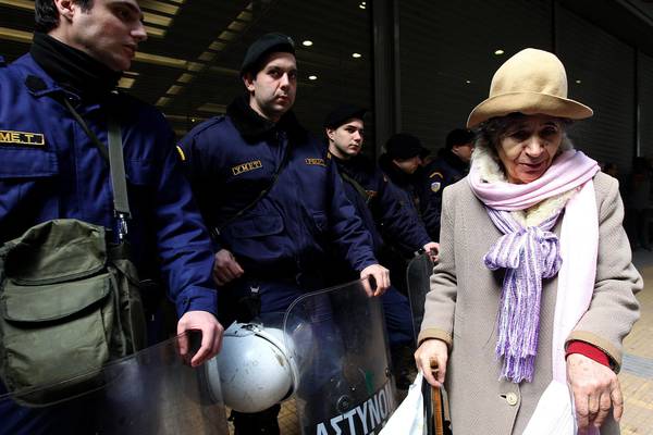 Un donna  davanti alla polizia antisommossa durante una manifestazione ad Atene contro gli aumenti dei prezzi dell'energia
