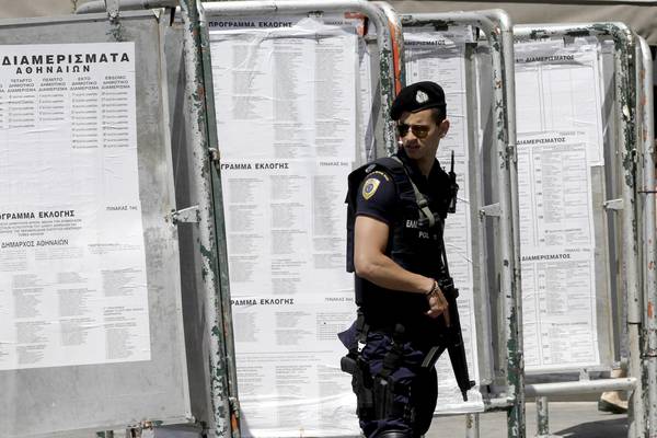 A police officer stands guard near banners with lists of the polling stations in the center of Athens, Greece