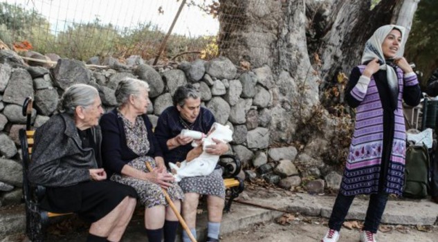 Photograph: Lefteris Partsalis. Le 'nonne' di Lesbo: Emilia Kamvisi e altre anziane donne aiutano un piccolo siriano