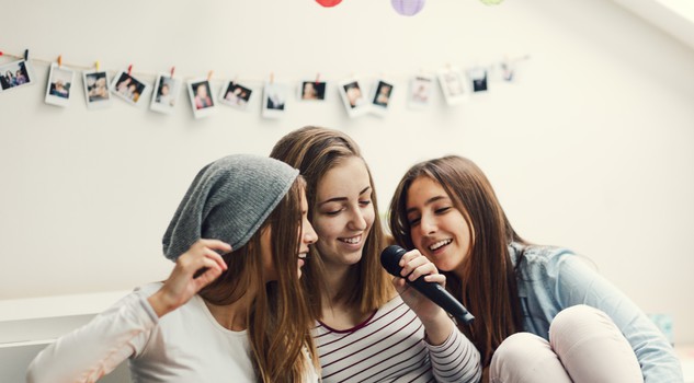 Tre ragazze e il karaoke con lo smartphone. ph. vgajic iStock.