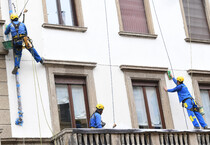 Operai acrobati al lavoro su un facciata di un palazzo a Milano (ANSA)