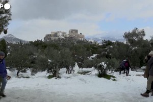 Gli abitanti di Atene si divertono con la neve sulle colline davanti all'Acropoli (ANSA)