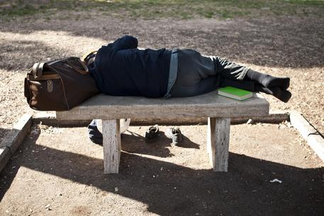 Un uomo dorme su una panchina in una foto di archivio © ANSA