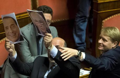 I Senatori del Movimento 5 stelle protestano contro il DDL e mostrano fotografie di Berlusconi e Napolitano © ANSA