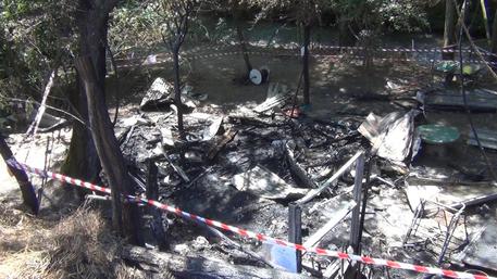 Si dà fuoco all'Aquila, i resti della baracchetta (foto: ANSA)