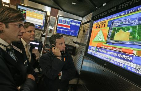 Operatori di borsa seguono in tv la notizia dell'aumento dei tassi di interesse deciso dalla Fed © AP