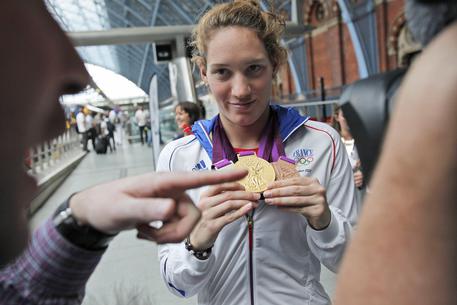 La nuotatrice francese Camille Muffat posa per i fotografi con le sue tre medaglie rispettivamente d'oro, d'argento e di bronzo vinte all'Olimpiade di Londra prima di partire dalla stazione di St.Pancras il 13 agosto 2012 © ANSA 