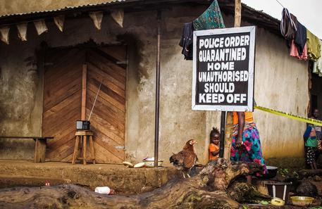 In questa foto d'archivio relativa al 22 ottobre 2014 un bambino si trova vicino a un cartello che avvisa di una casa in quarantena a Port Loko, in Sierra Leone © AP