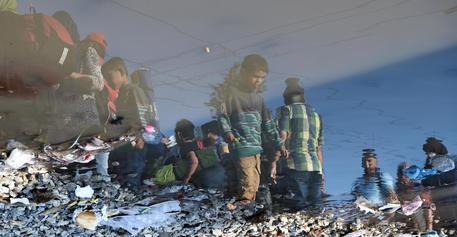Migranti, riflessi nelle pozzanghere, lasciano il villaggio di Idomeni verso la Macedonia © AP
