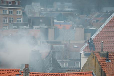 Un poliziotto su un tetto mentre il fumo esce da un camino © EPA