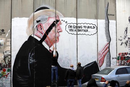 Palestinesi disegnano una X sul poster di Trump a Betlemme, in Cisgiordania © EPA