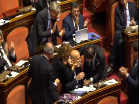 Un fermo immagine di un video mostra alcuni senatori che si congratulano con  Augusto Minzolini dopo il voto contro la sua decadenza © ANSA