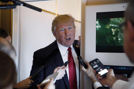 Donald Trump parla ai giornalisti a bordo dell'Air Force One con Guerre Stellari alle spalle © AP