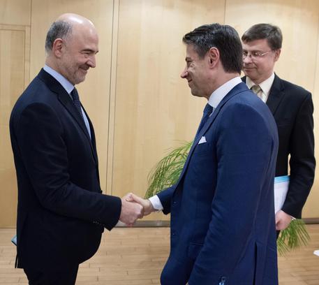 Stretta di mano tra il commissario Ue per gli affari economici Pierre Moscovici e il presidente  del Consiglio Giuseppe Conte in una foto di archivio © ANSA