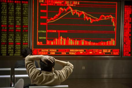 Un investitore segue sul monitor l'andamento di Borsa in Cina © AP