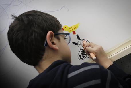 Un bambino disegna al MAXXI durante l'incontro delle famiglie degli autistici (in occasione della Giornata Mondiale sull'autismo). Immagine d'archivio © ANSA