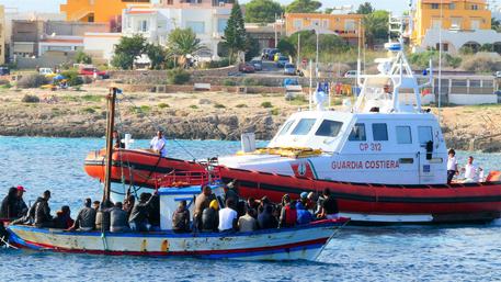 Migranti a bordo di un barcone entrano nel porto di Lampedusa. Immagine d'archivio © ANSA