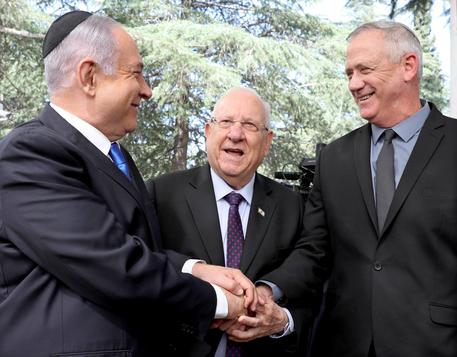 Banyamin Netanyahu (s) e benny Gantz (d) si stringono la mano davanti al presidente d'Israele, Reuven Rivlin (c) © EPA