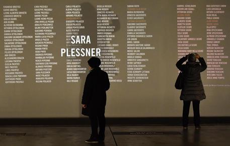 Due donne osservano una parete sulla quale sono proiettati i nomi degli ebrei italiani deportati nei campi di sterminio nazisti al Memoriale della Shoah di Milano © ANSA