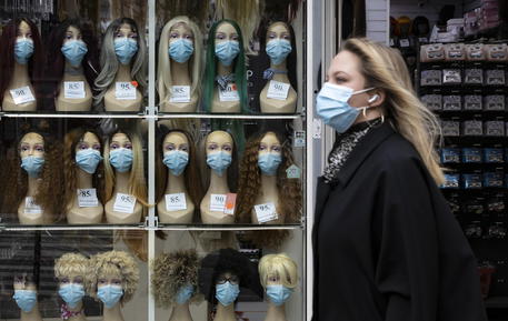 Una donna passa vicino a un negozio con alcuni manichini con le mascherine a Parigi © EPA