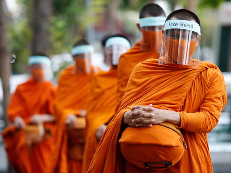 Monaci buddisti con visiere protettive a Bangkok © EPA