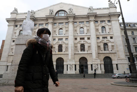 Una donna con la mascherina davanti a Piazza Affari © 